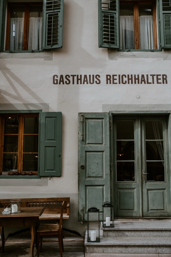The front of Gasthaus Reichhalter with green shutters and candle lanterns by the door