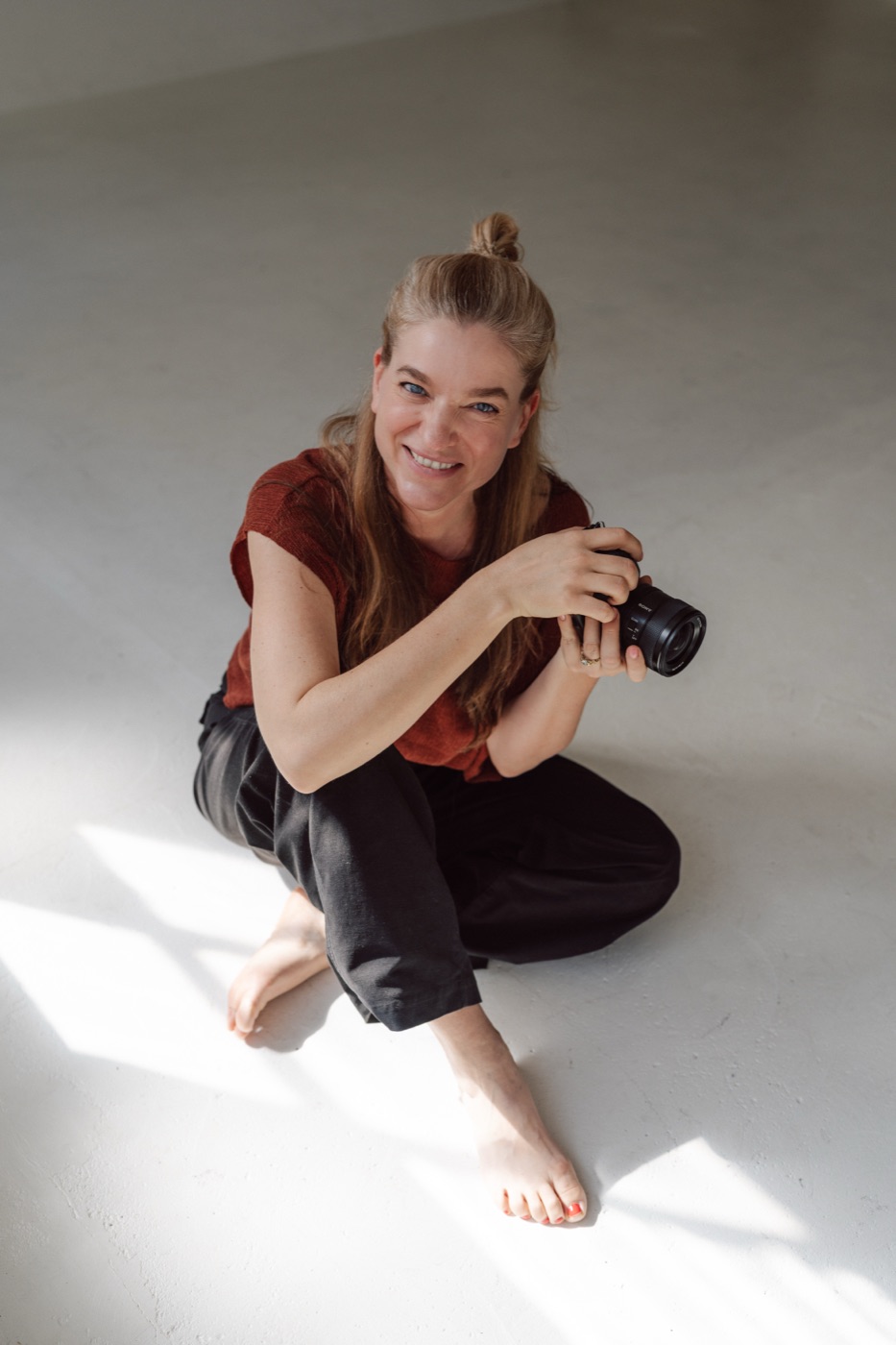 Vera Prinz, founder of Voyant Visuals, sitting on the floor with her camera